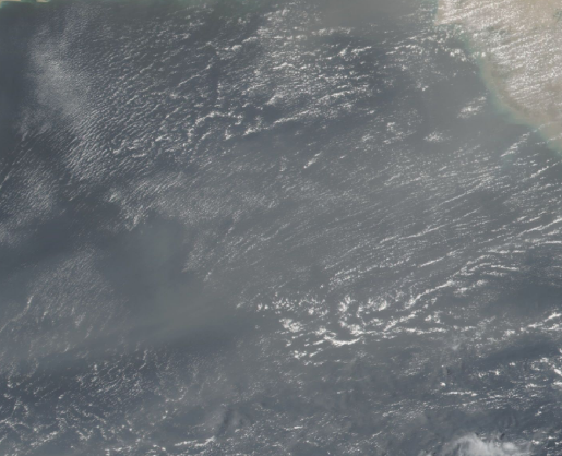 An aerial image with potential sandstorms, or clouds, over a body of water. 