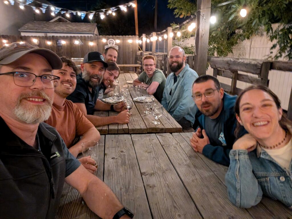 Sprint attendees around a table during the sprint happy hour. 