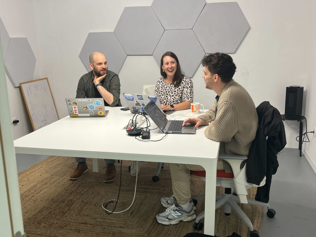 Three tasking sprinters working on laptops sitting at a table. 